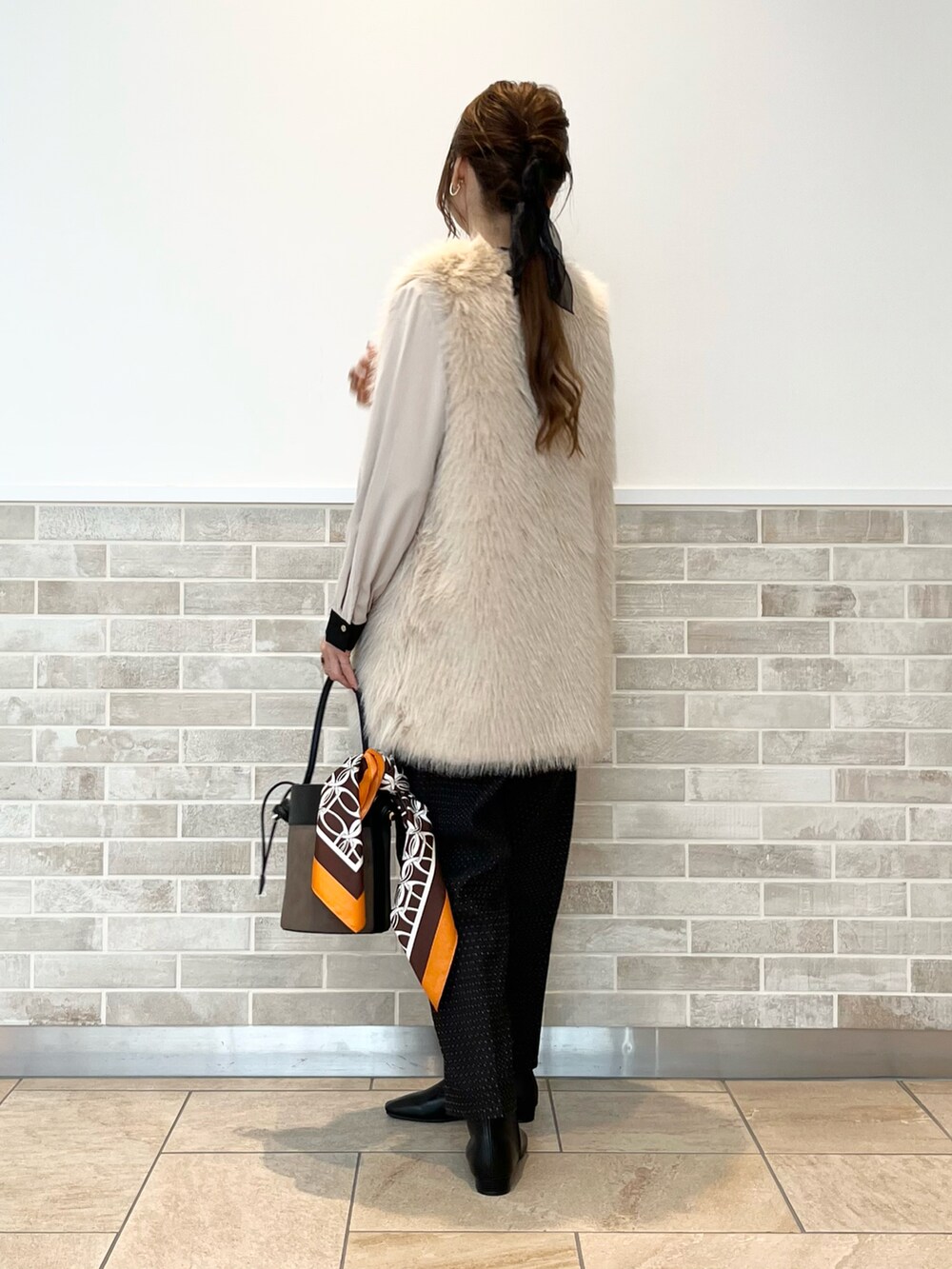 ベージュ系のベスト、ベージュ系のシャツ/ブラウス、ブラウン系のハンドバッグを着用したレディースの秋コーディネートの3枚目の写真