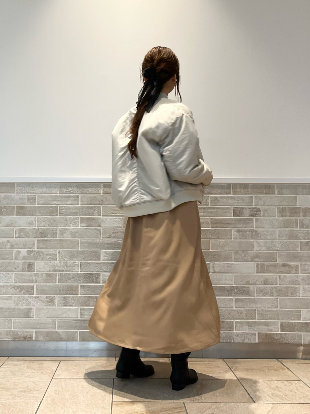 ベージュ系のブルゾン、ベージュ系のワンピース、ブラック系のブーツを着用したレディースの秋コーディネートの2枚目の写真