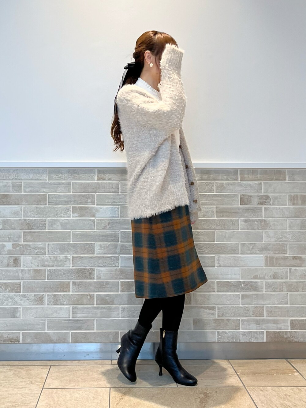 オレンジ系のスカート、ホワイト系のシャツ/ブラウス、ベージュ系のニット/セーターを着用したレディースの秋コーディネートの2枚目の写真