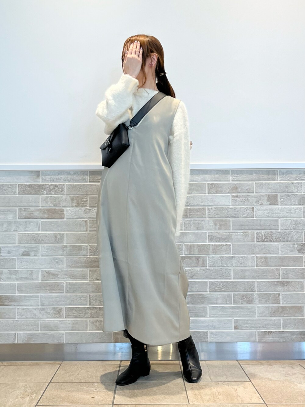 グリーン系のワンピース、ホワイト系のニット/セーター、ブラック系のブーツを着用したレディースの冬コーディネートの3枚目の写真