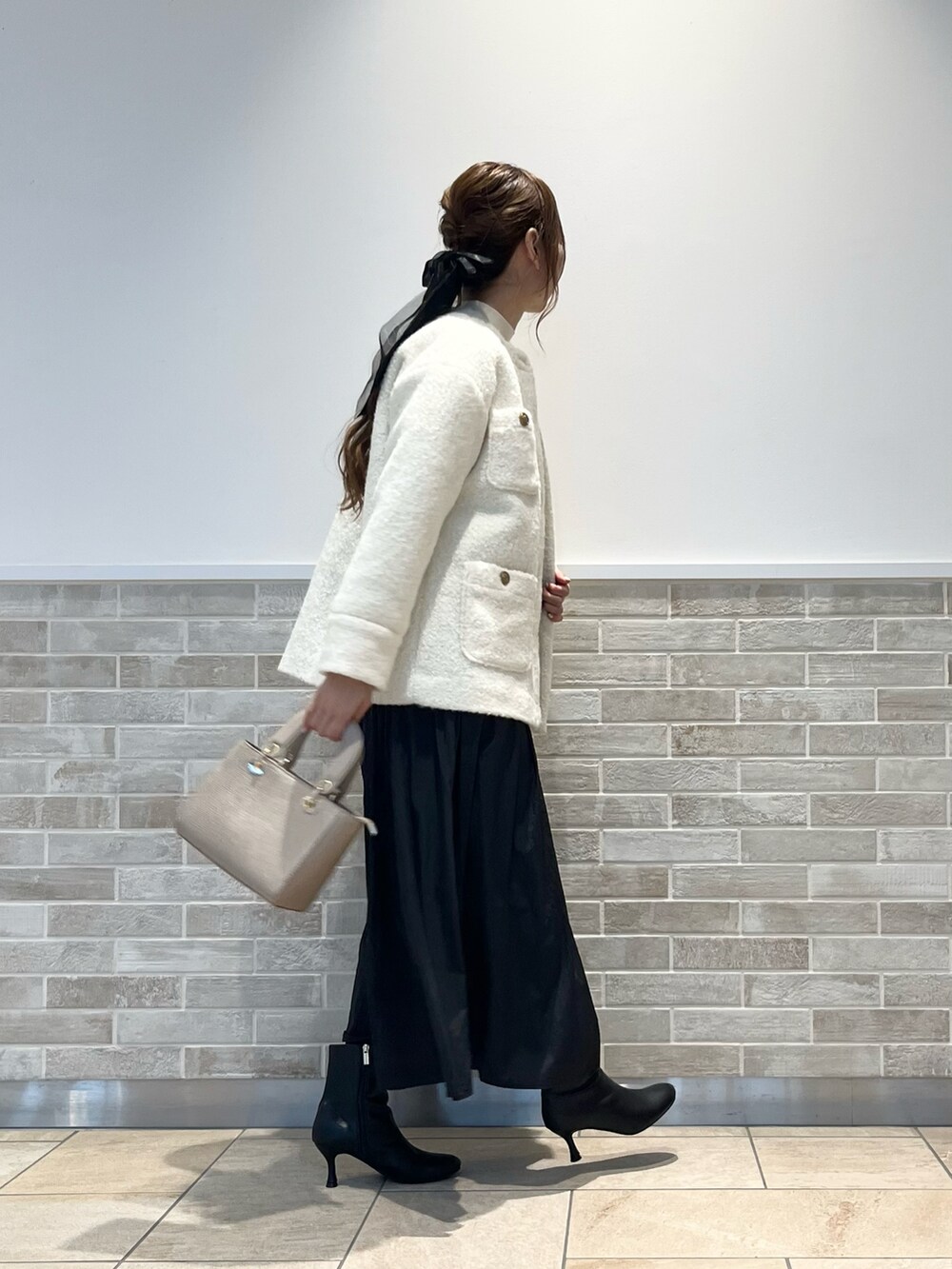 ホワイト系のその他アウター、ホワイト系のニット/セーター、ブラック系のスカートを着用したレディースの秋コーディネートの2枚目の写真