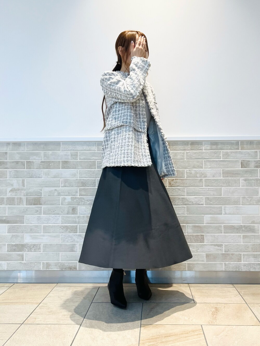 ホワイト系のノーカラージャケット、グレー系のスカート、ブラック系のブーツを着用したレディースの冬コーディネートの2枚目の写真