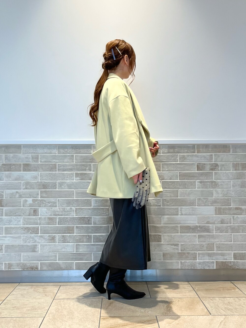 ブラック系のスカート、ブラック系のブーツ、イエロー系のその他アウターを着用したレディースの秋コーディネートの3枚目の写真