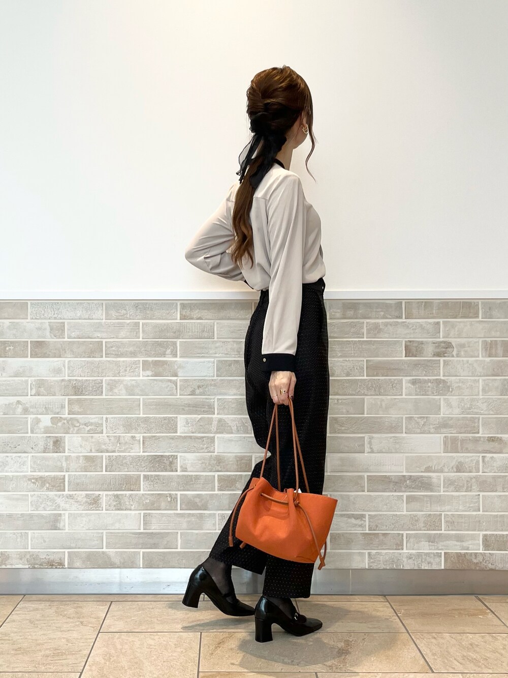 ブラック系のその他パンツ、ベージュ系のシャツ/ブラウス、オレンジ系のハンドバッグを着用したレディースの秋コーディネートの5枚目の写真