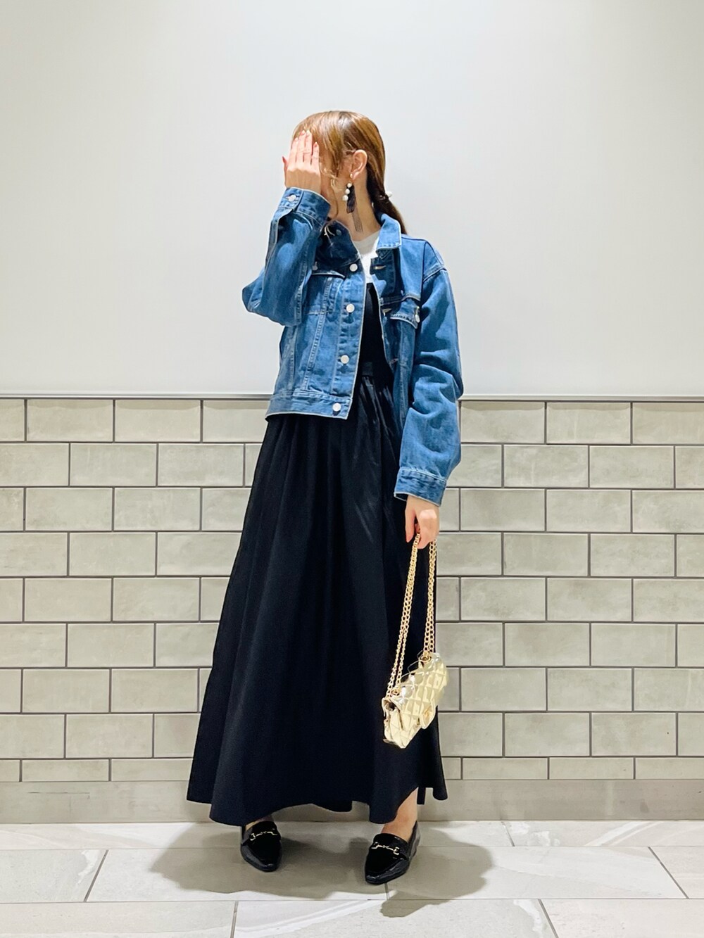 ブラック系のワンピース、ゴールド系のハンドバッグ、ブラック系のローファーを着用したレディースの夏コーディネートの4枚目の写真