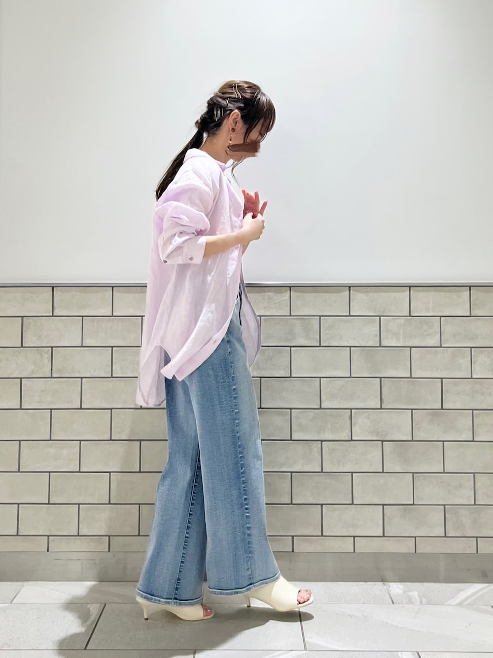 ブルー系のデニムパンツ、ホワイト系のサンダル、ピンク系のシャツ/ブラウスを着用したレディースの春コーディネートの3枚目の写真