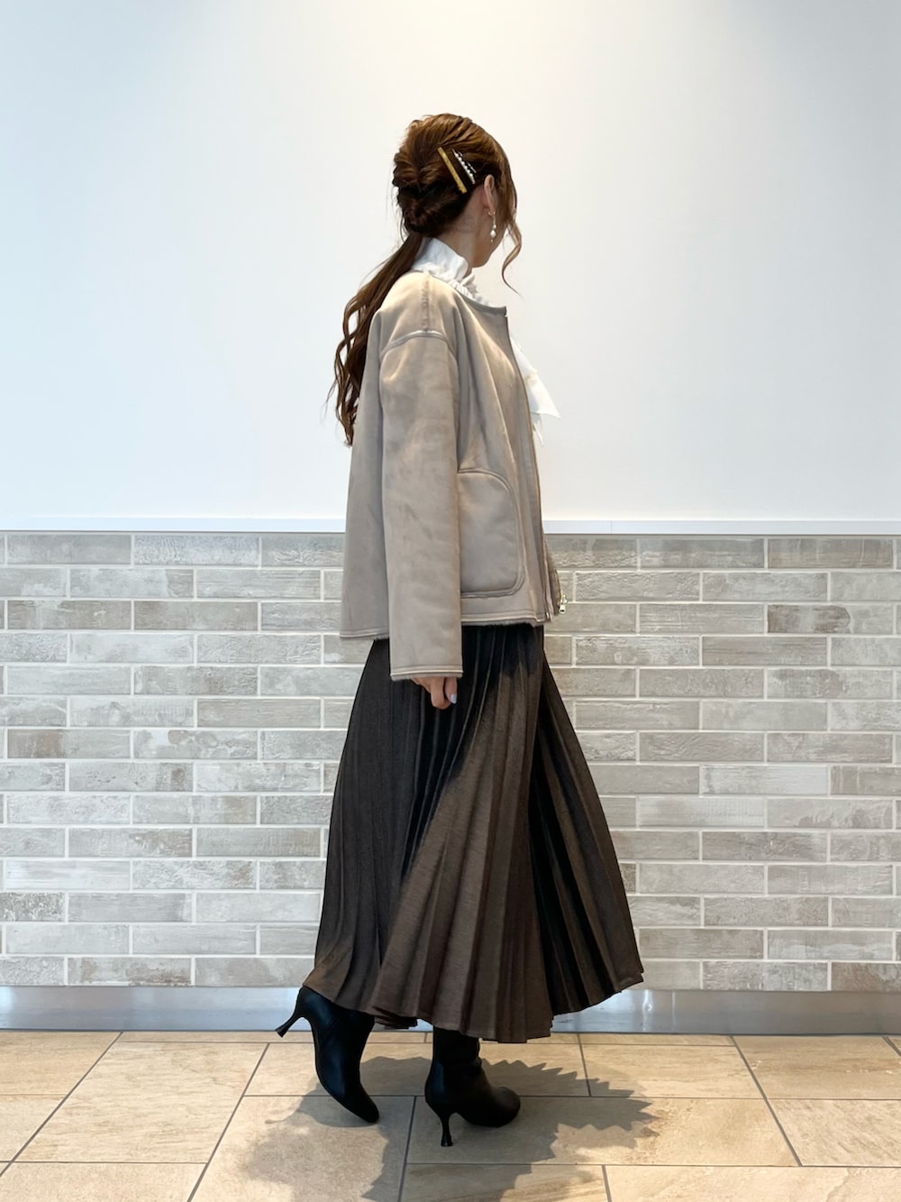 ブラウン系のスカート、ホワイト系のシャツ/ブラウス、ブラウン系のブルゾンを着用したレディースの冬コーディネートの3枚目の写真