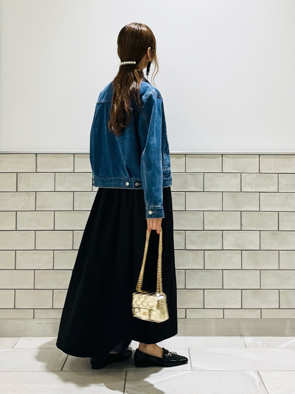 ブラック系のワンピース、ゴールド系のハンドバッグ、ブラック系のローファーを着用したレディースの夏コーディネートの3枚目の写真