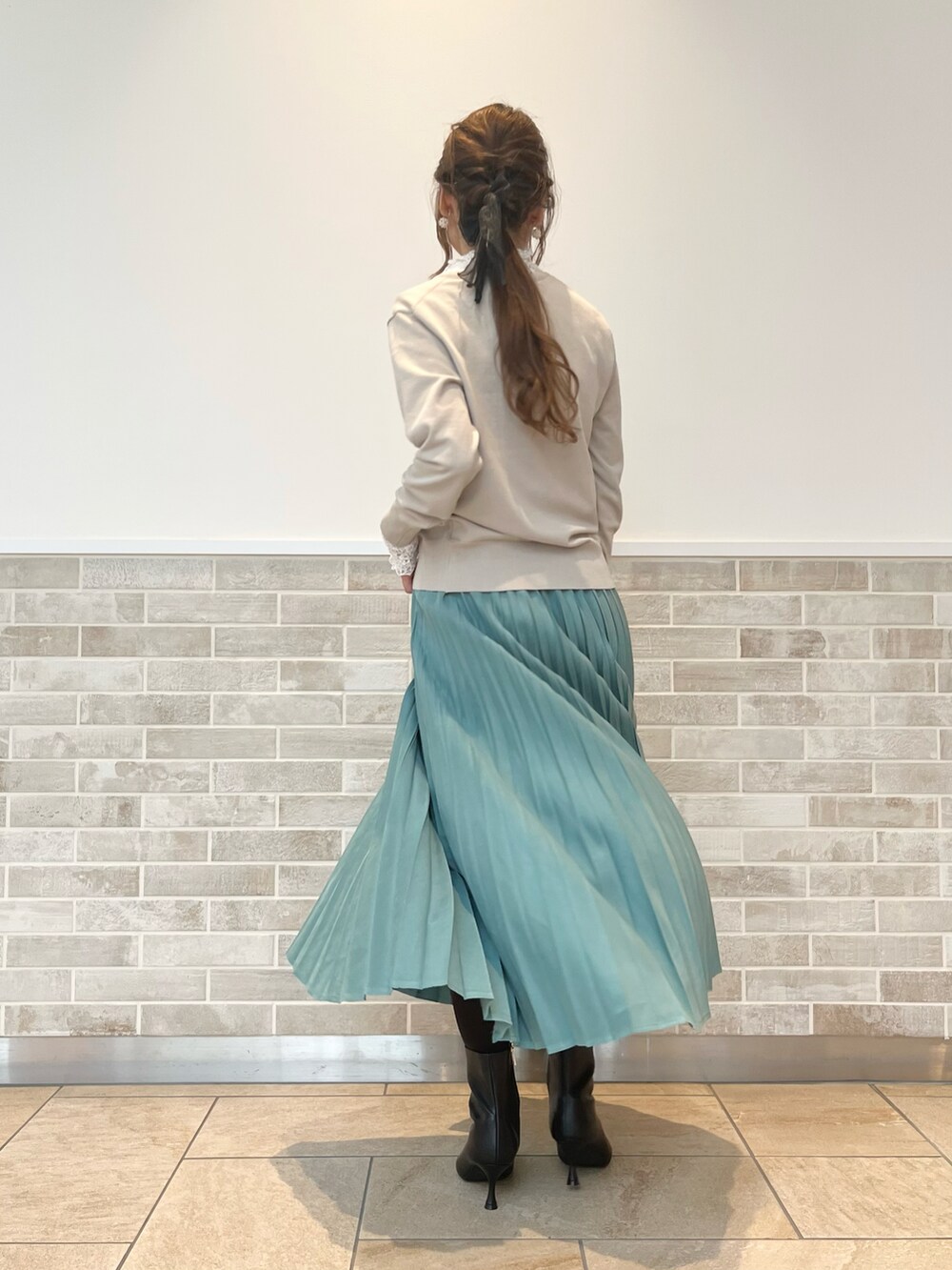 ブラック系のブーツ、グリーン系のスカート、ベージュ系のハンドバッグを着用したレディースの秋コーディネートの4枚目の写真