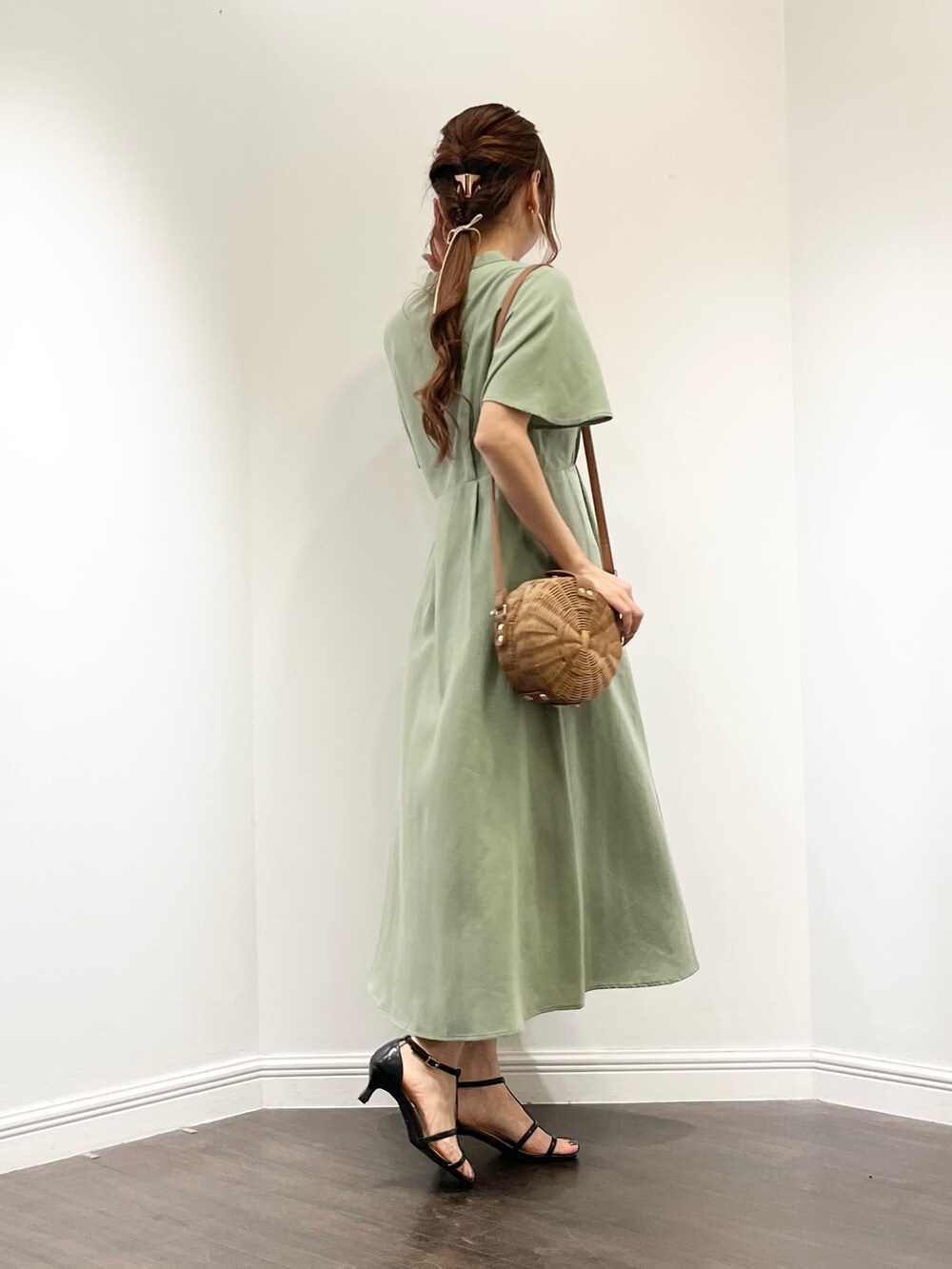 グリーン系のワンピース、ブラック系のサンダル、ブラウン系のバッグを着用したレディースの春コーディネートの2枚目の写真