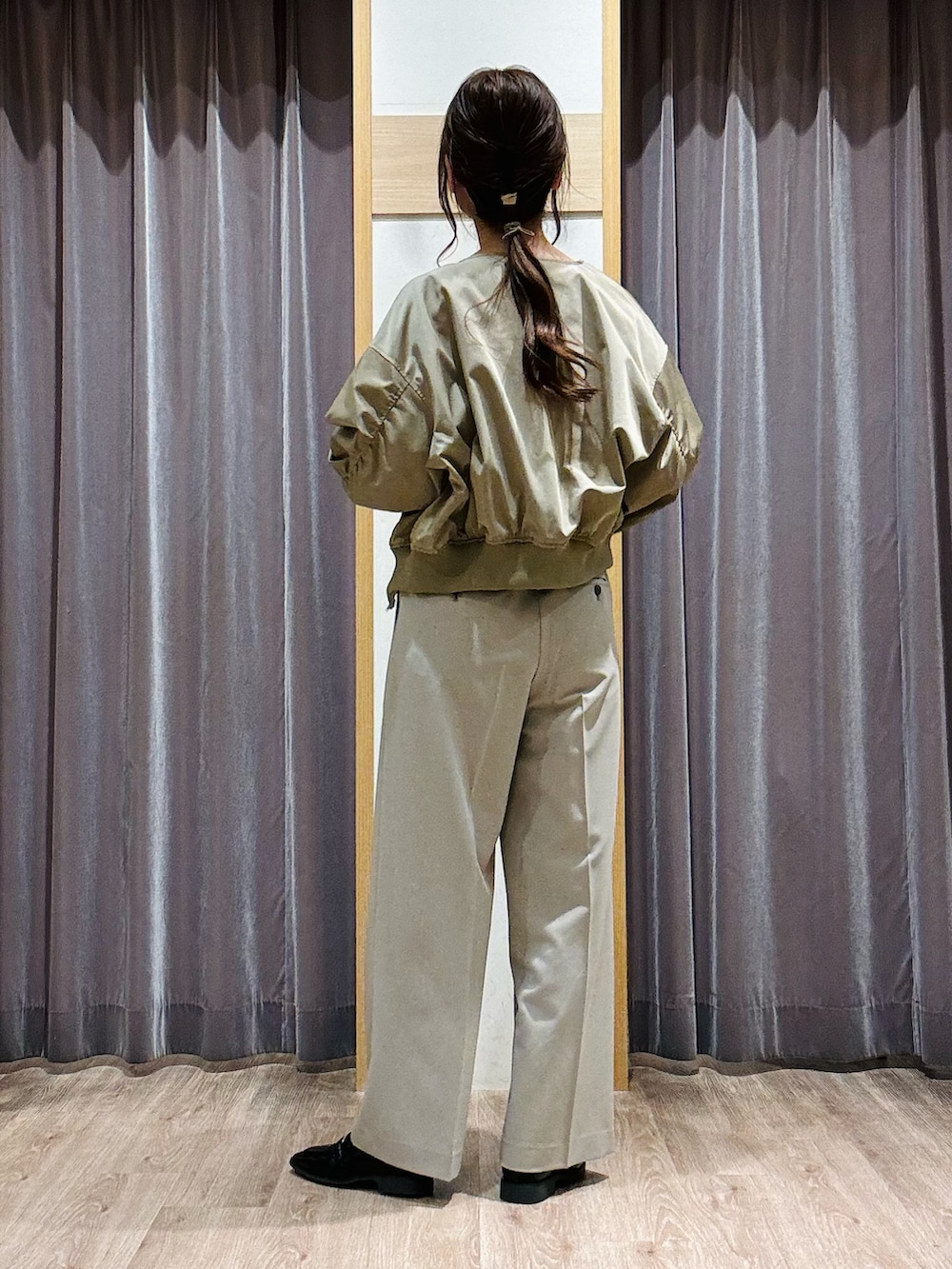 グリーン系のニット/セーター、ベージュ系のその他パンツ、ブラック系のハンドバッグを着用したレディースの春コーディネートの4枚目の写真