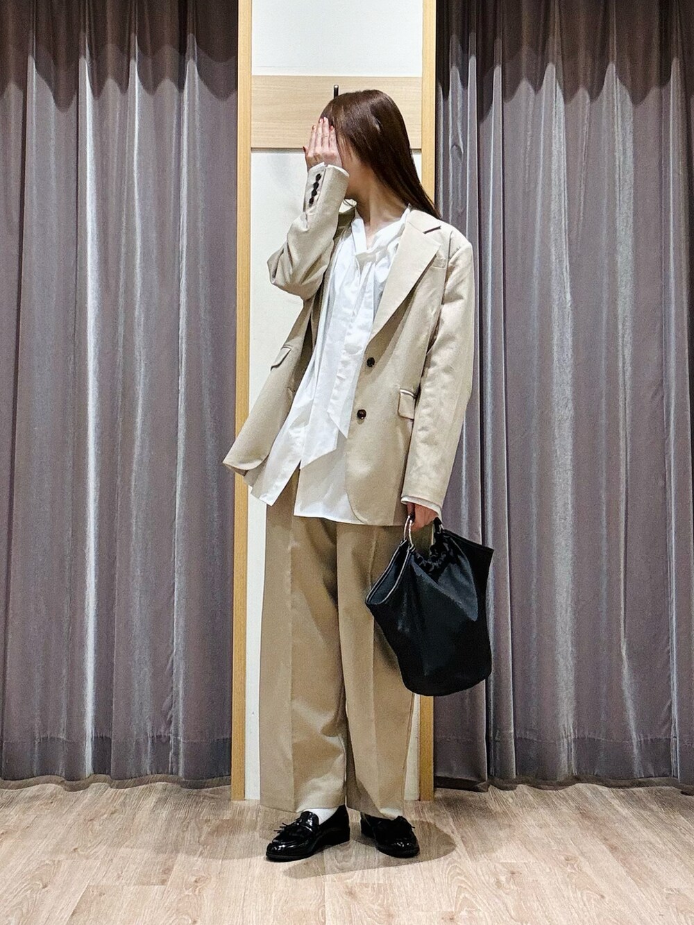 ブラック系のハンドバッグ、ベージュ系のノーカラージャケット、ベージュ系のその他パンツを着用したレディースの春コーディネートの3枚目の写真