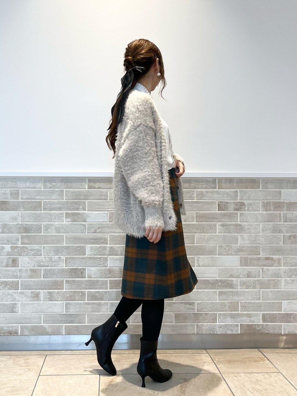 オレンジ系のスカート、ホワイト系のシャツ/ブラウス、ベージュ系のニット/セーターを着用したレディースの秋コーディネートの4枚目の写真
