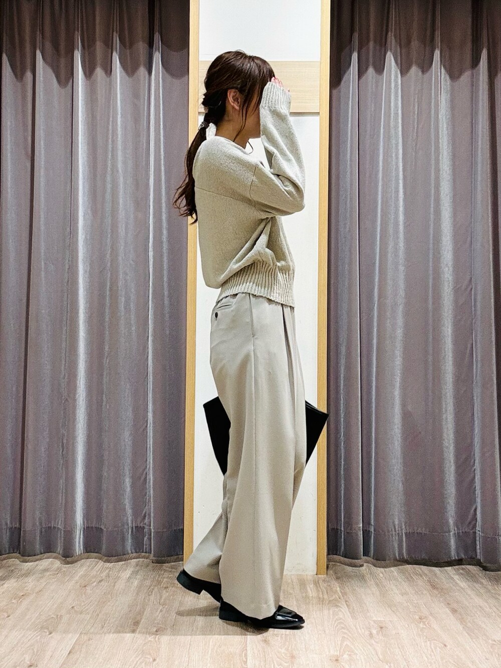 グリーン系のニット/セーター、ベージュ系のその他パンツ、ブラック系のハンドバッグを着用したレディースの春コーディネートの2枚目の写真