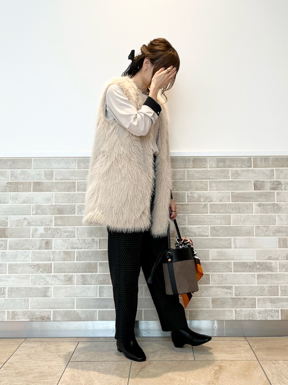 ベージュ系のベスト、ベージュ系のシャツ/ブラウス、ブラウン系のハンドバッグを着用したレディースの秋コーディネートの4枚目の写真