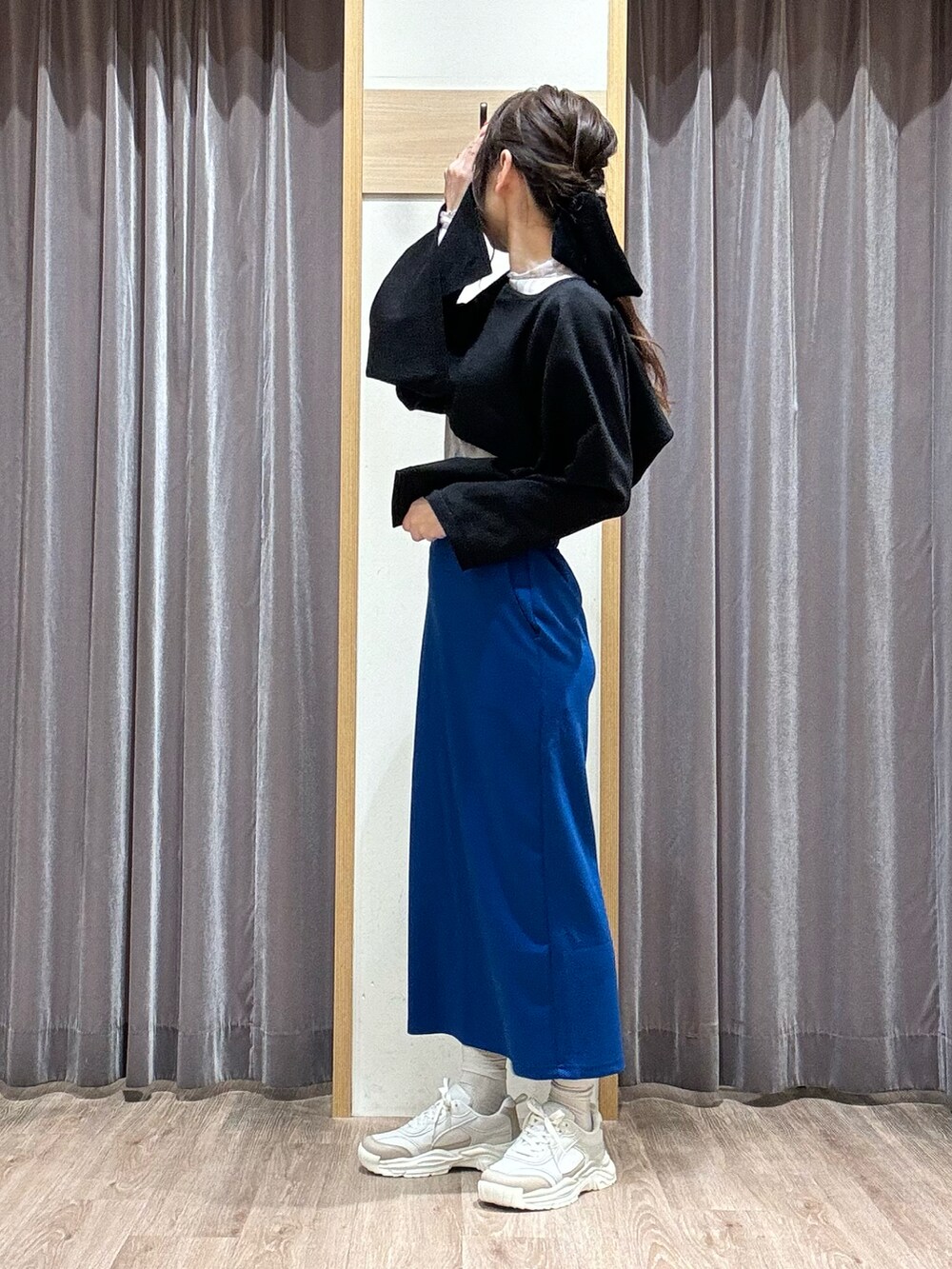 ブルー系のスカート、ブラック系のニット/セーター、ブルー系のTシャツ/カットソーを着用したレディースの春コーディネートの2枚目の写真