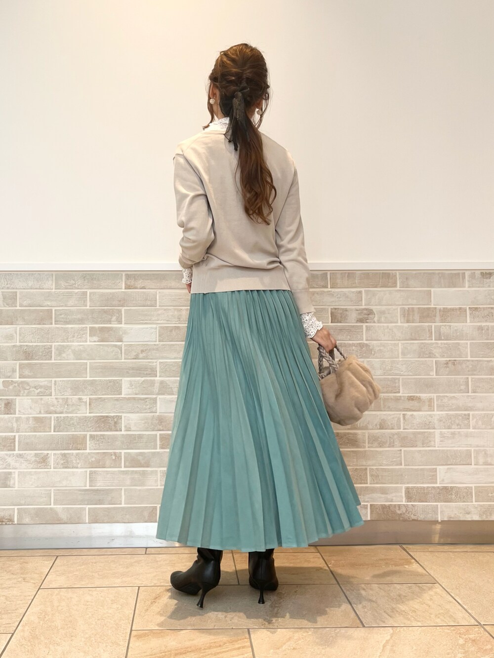 ブラック系のブーツ、グリーン系のスカート、ベージュ系のハンドバッグを着用したレディースの秋コーディネートの2枚目の写真