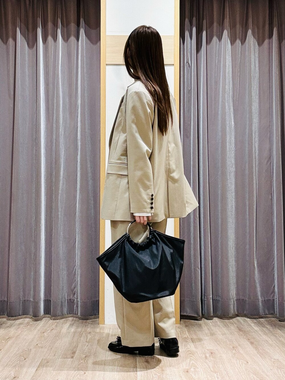 ブラック系のハンドバッグ、ベージュ系のノーカラージャケット、ベージュ系のその他パンツを着用したレディースの春コーディネートの4枚目の写真