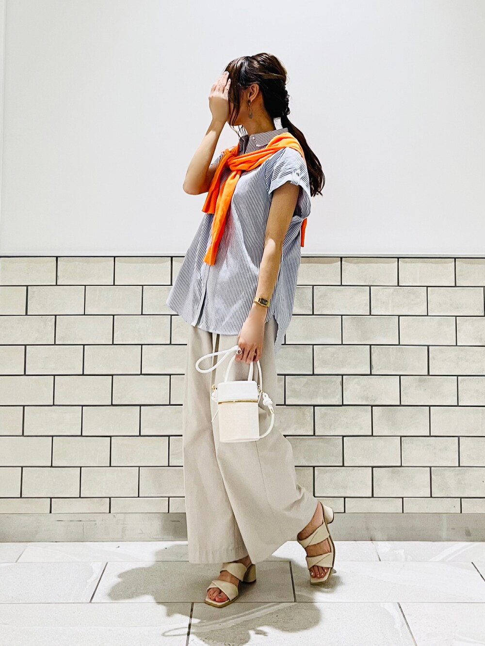 ホワイト系のサンダル、ブルー系のシャツ/ブラウス、ホワイト系のハンドバッグを着用したレディースの夏コーディネートの2枚目の写真