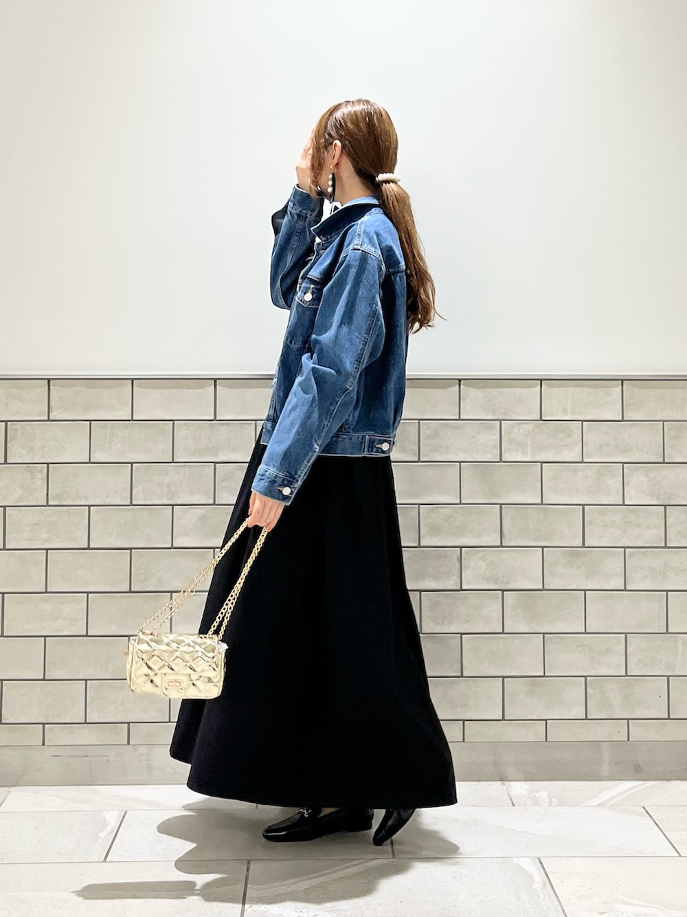 ブラック系のワンピース、ゴールド系のハンドバッグ、ブラック系のローファーを着用したレディースの夏コーディネートの2枚目の写真