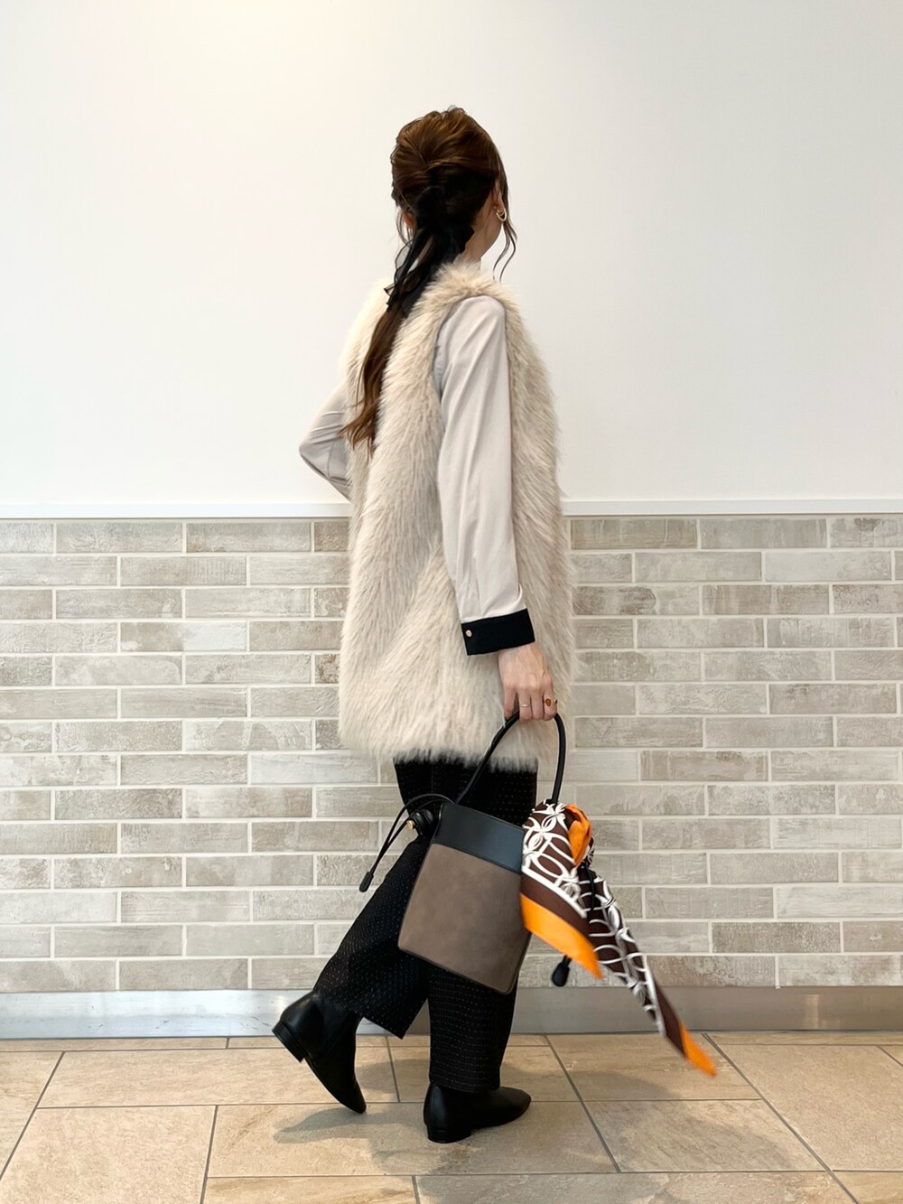 ベージュ系のベスト、ベージュ系のシャツ/ブラウス、ブラウン系のハンドバッグを着用したレディースの秋コーディネートの5枚目の写真