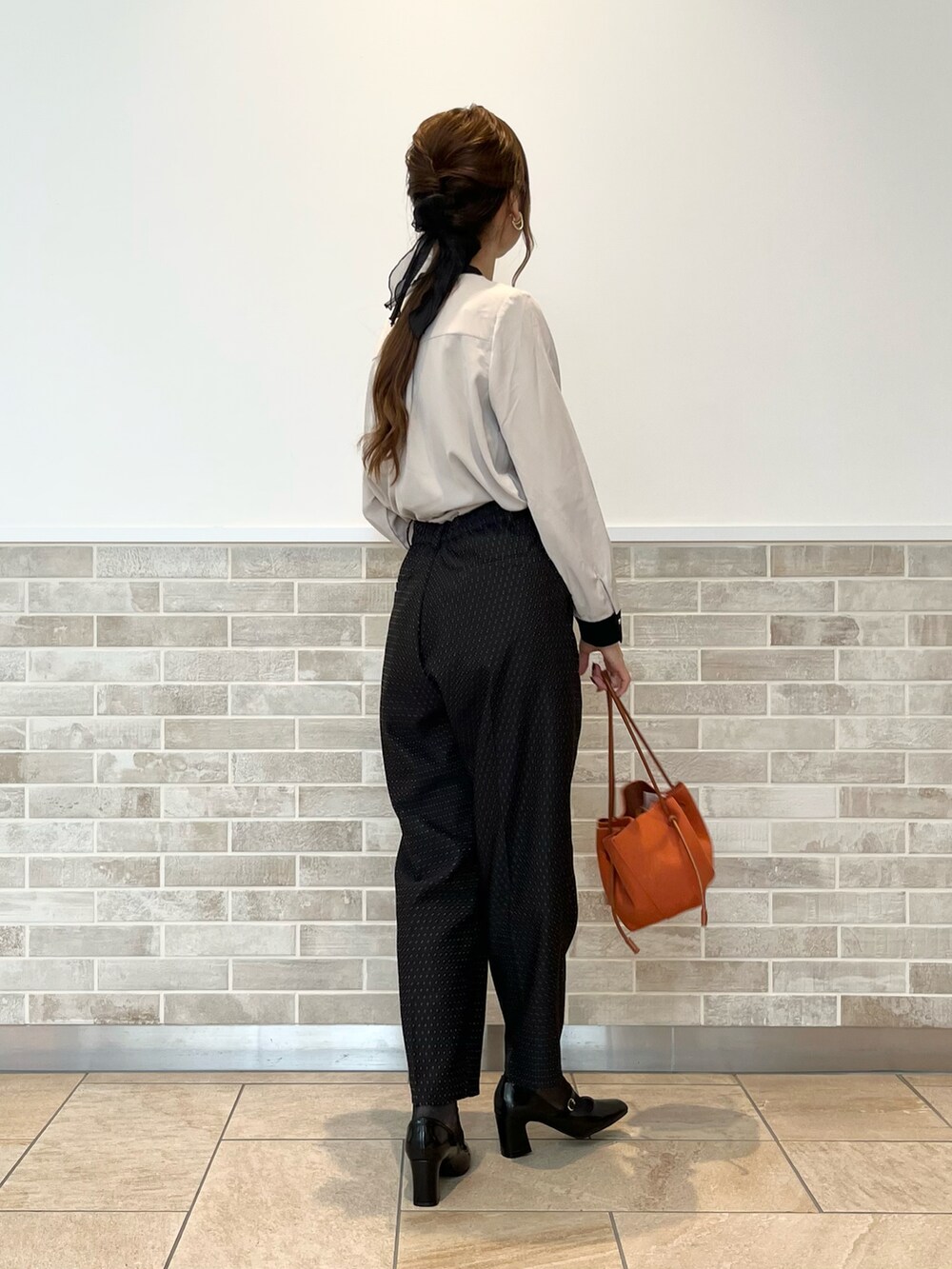 ブラック系のその他パンツ、ベージュ系のシャツ/ブラウス、オレンジ系のハンドバッグを着用したレディースの秋コーディネートの3枚目の写真