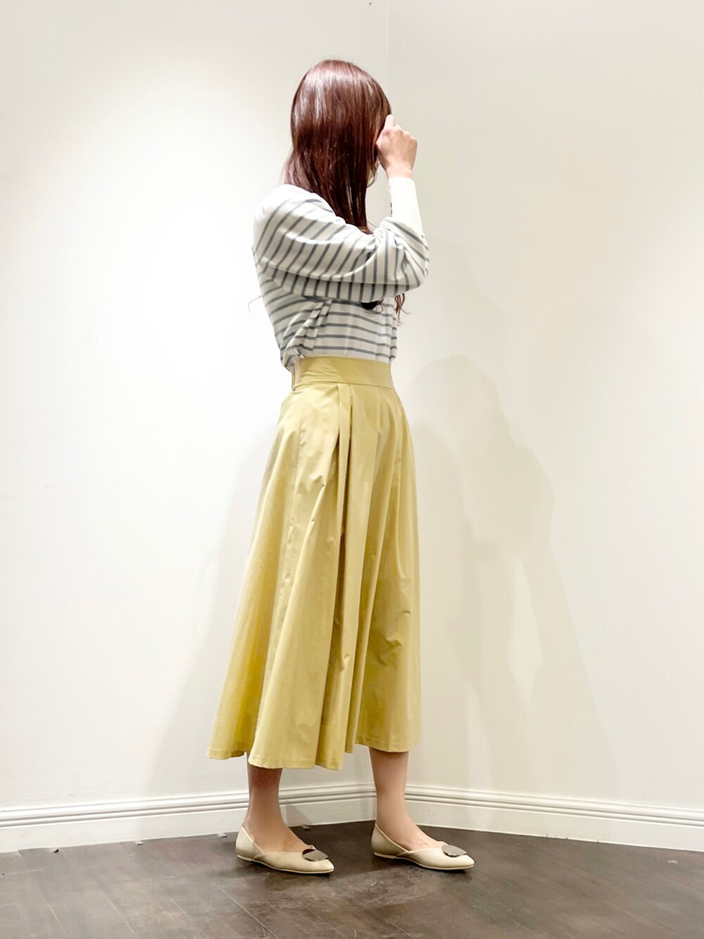 ブルー系のニット/セーター、イエロー系のスカート、ホワイト系のパンプスを着用したレディースの春コーディネートの3枚目の写真