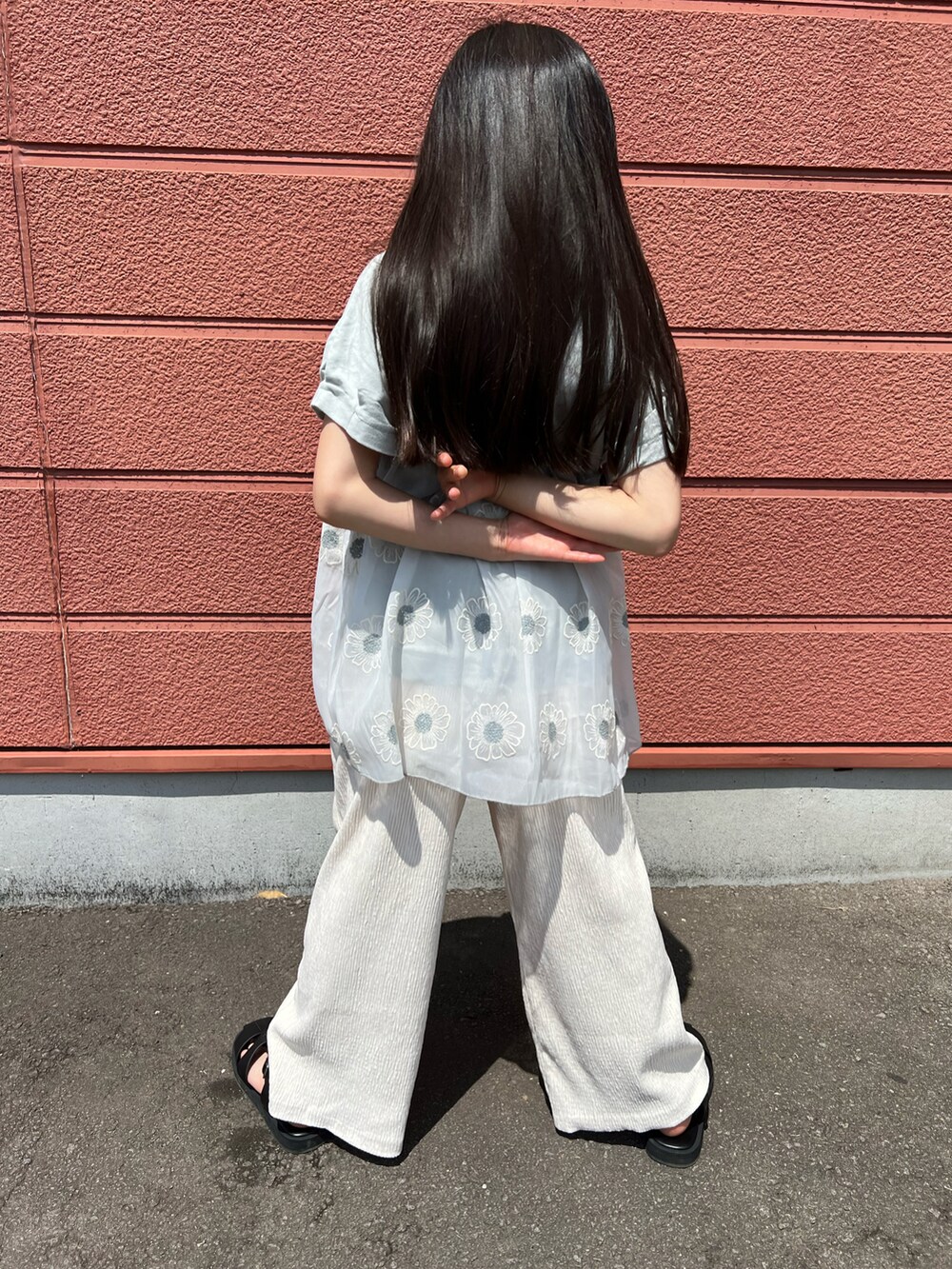 グリーン系のチュニック、ホワイト系のその他パンツ、ブラック系のサンダルを着用したキッズの春コーディネートの3枚目の写真