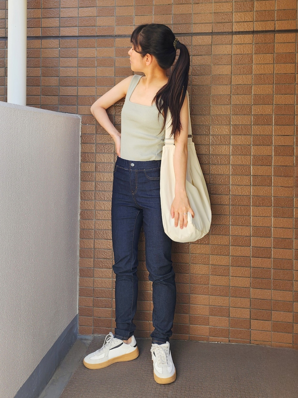 グリーン系のタンクトップ、ブルー系のデニムパンツ、ホワイト系のシャツ/ブラウスを着用したレディースの春コーディネートの2枚目の写真