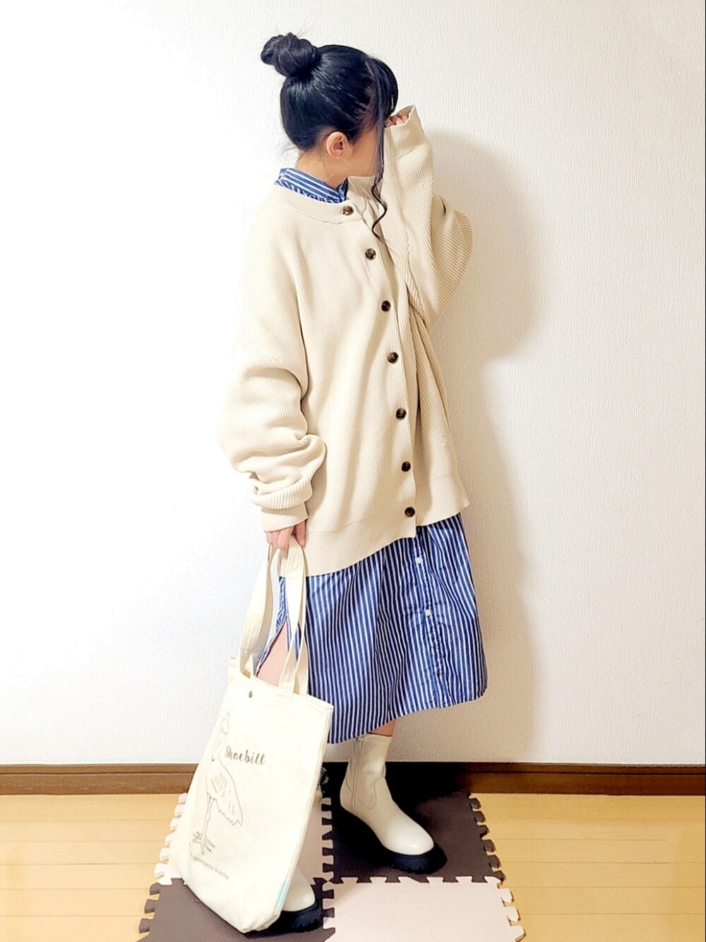 ベージュ系のカーディガン/ボレロ、ブルー系のシャツワンピース、ホワイト系のブーツを着用したレディースの冬コーディネートの2枚目の写真