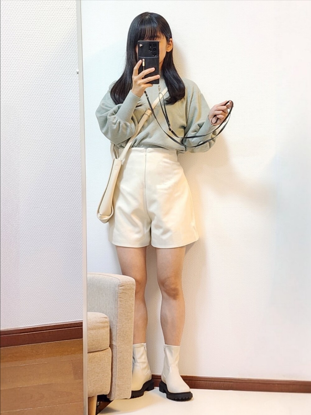 ベージュ系のダウンジャケット/コート、ホワイト系のブーツ、グリーン系のニット/セーターを着用したレディースの秋コーディネートの2枚目の写真