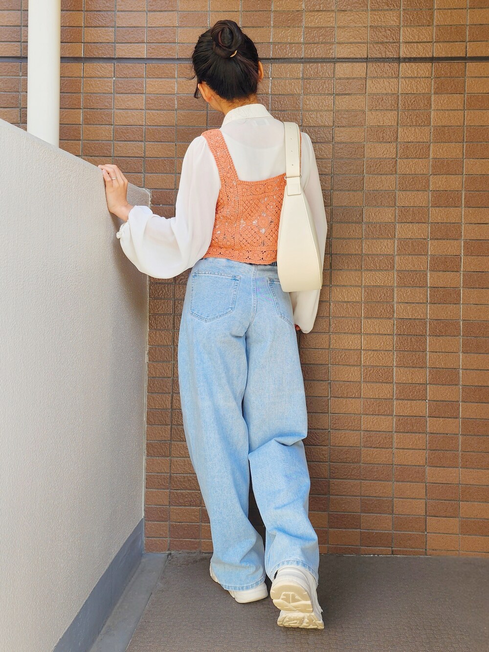 オレンジ系のニット/セーター、ホワイト系のシャツ/ブラウス、ブルー系のデニムパンツを着用したレディースの春コーディネートの2枚目の写真