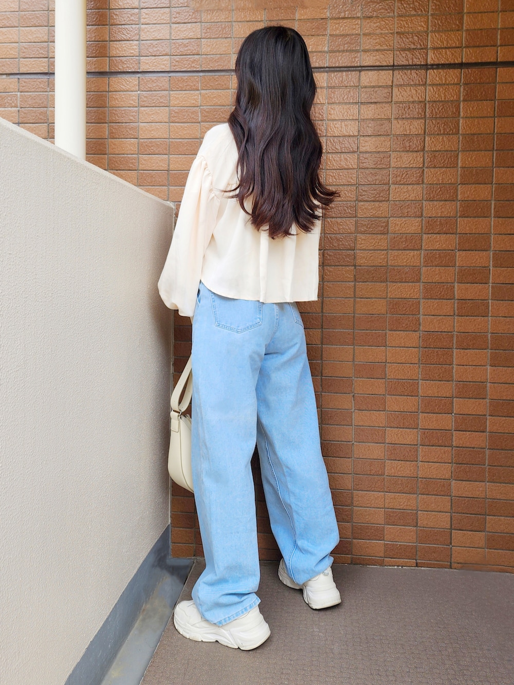 ブルー系のデニムパンツ、ホワイト系のスニーカー、ホワイト系のバッグを着用したレディースの春コーディネートの2枚目の写真