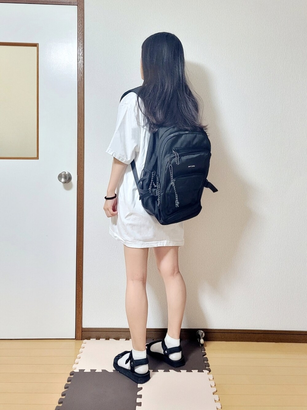 ホワイト系のTシャツ/カットソー、ブラック系のサンダル、ブラック系のバックパック/リュックを着用したレディースの夏コーディネートの2枚目の写真