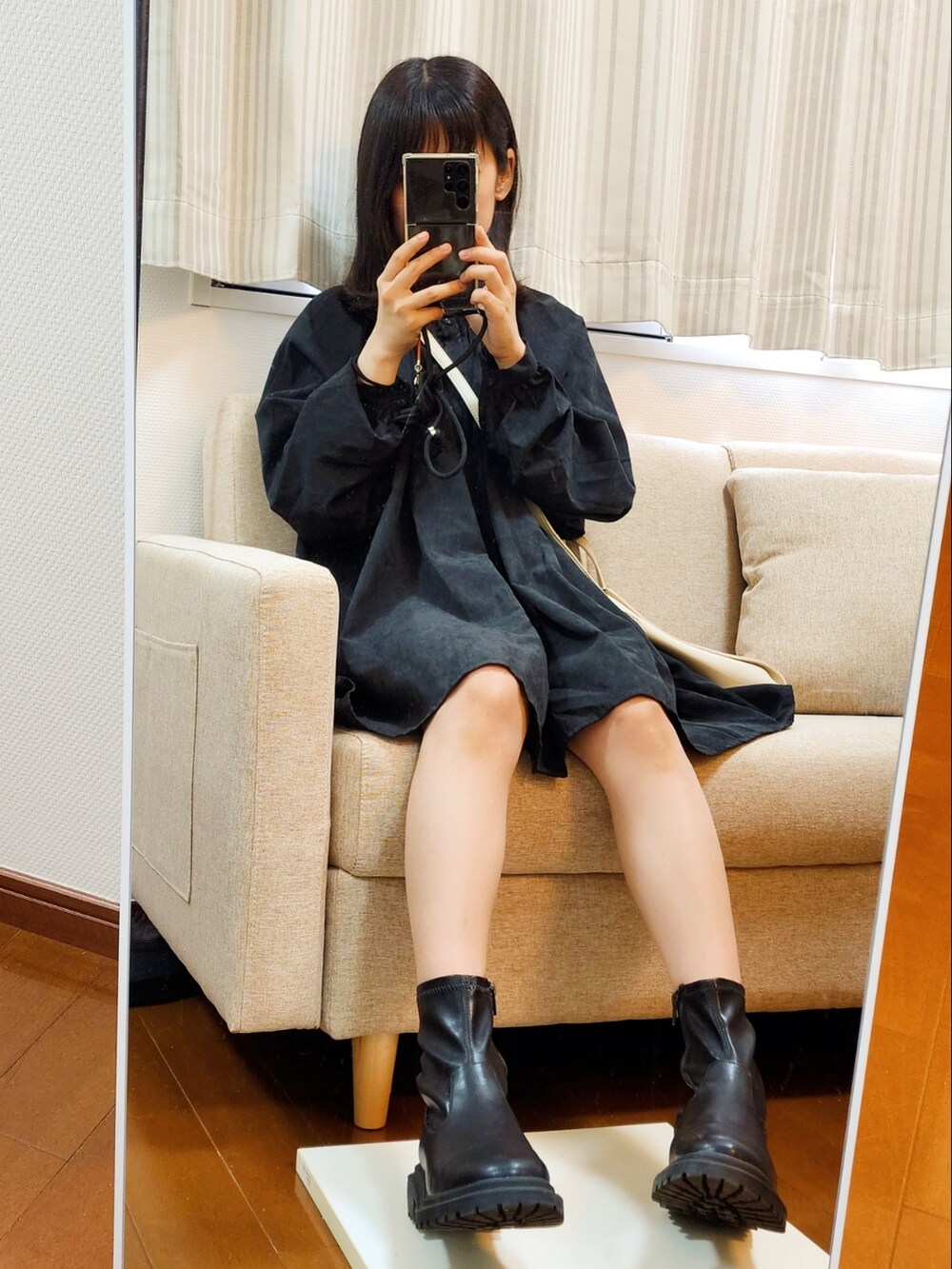 ブラック系のワンピース、ホワイト系のトートバッグ、ブラック系のブーツを着用したレディースの春コーディネートの2枚目の写真