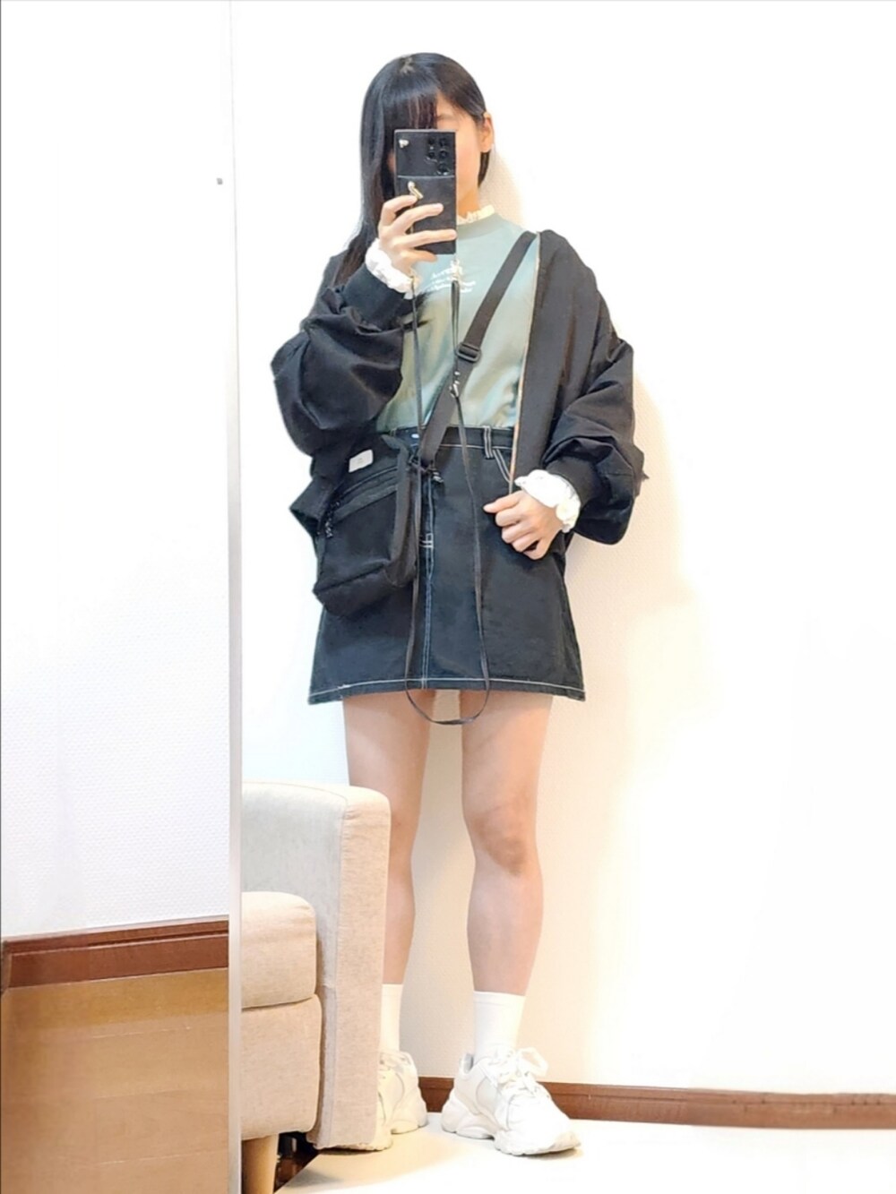 グリーン系のスウェット、ブラック系のスカート、ブラック系のショルダーバッグを着用したレディースの冬コーディネートの2枚目の写真