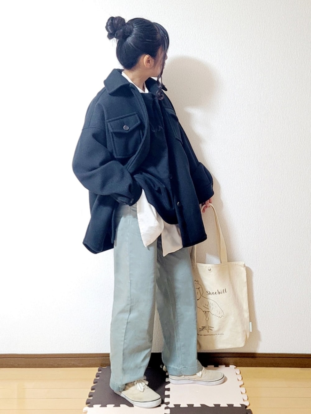 グリーン系のデニムパンツ、ベージュ系のスニーカー、ホワイト系のトートバッグを着用したレディースの秋コーディネートの2枚目の写真