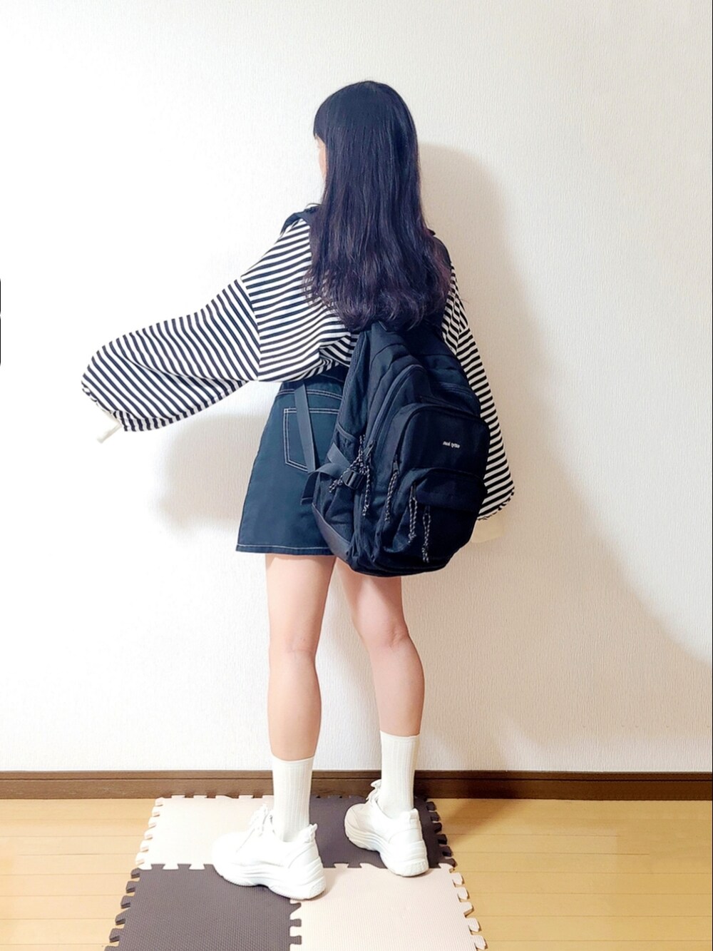 ホワイト系のTシャツ/カットソー、ブラック系のスカート、ホワイト系のスニーカーを着用したレディースの秋コーディネートの2枚目の写真