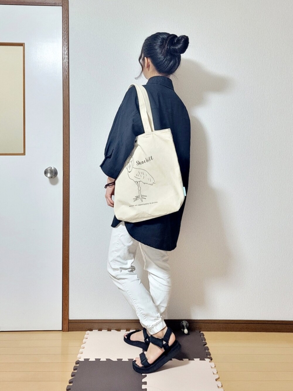 ブラック系のシャツ/ブラウス、ホワイト系のチノパンツ、ホワイト系のトートバッグを着用したレディースの夏コーディネートの2枚目の写真