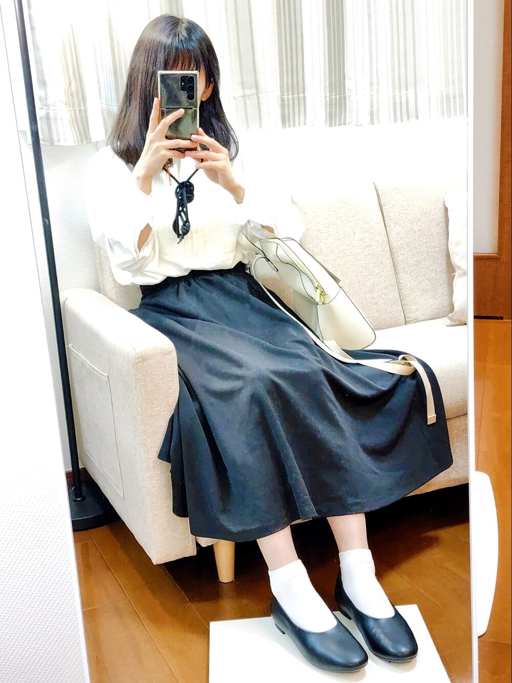 ホワイト系のシャツ/ブラウス、ブラック系のスカート、ベージュ系のバックパック/リュックを着用したレディースの春コーディネートの2枚目の写真