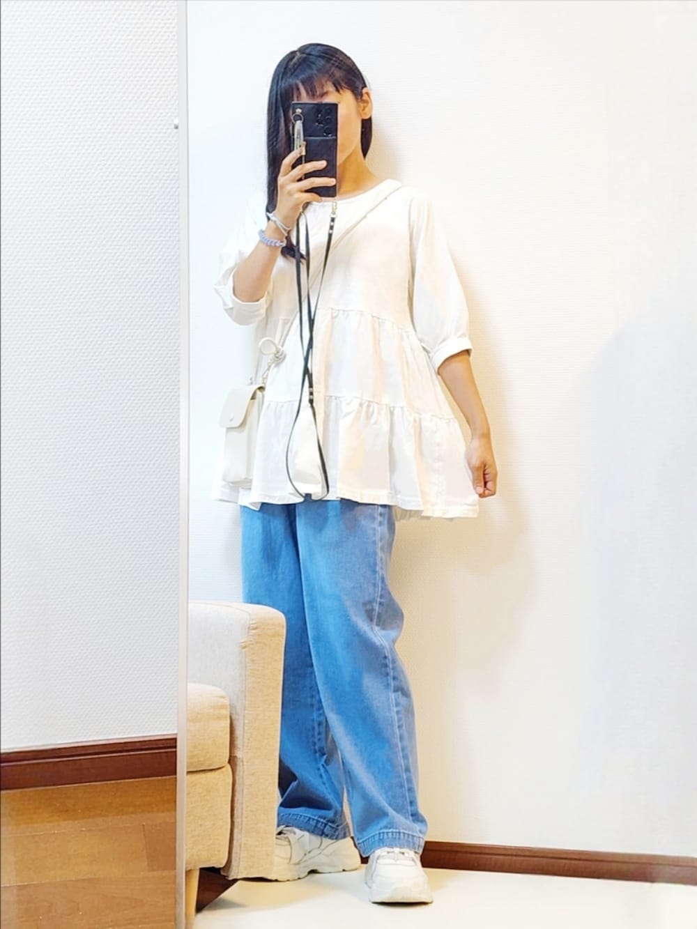 ホワイト系のチュニック、ブルー系のデニムパンツ、ホワイト系のスニーカーを着用したレディースの夏コーディネートの2枚目の写真