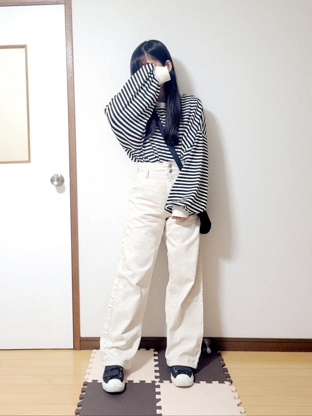 ホワイト系のTシャツ/カットソー、ブラック系のショルダーバッグ、ホワイト系のデニムパンツを着用したレディースの秋コーディネートの2枚目の写真