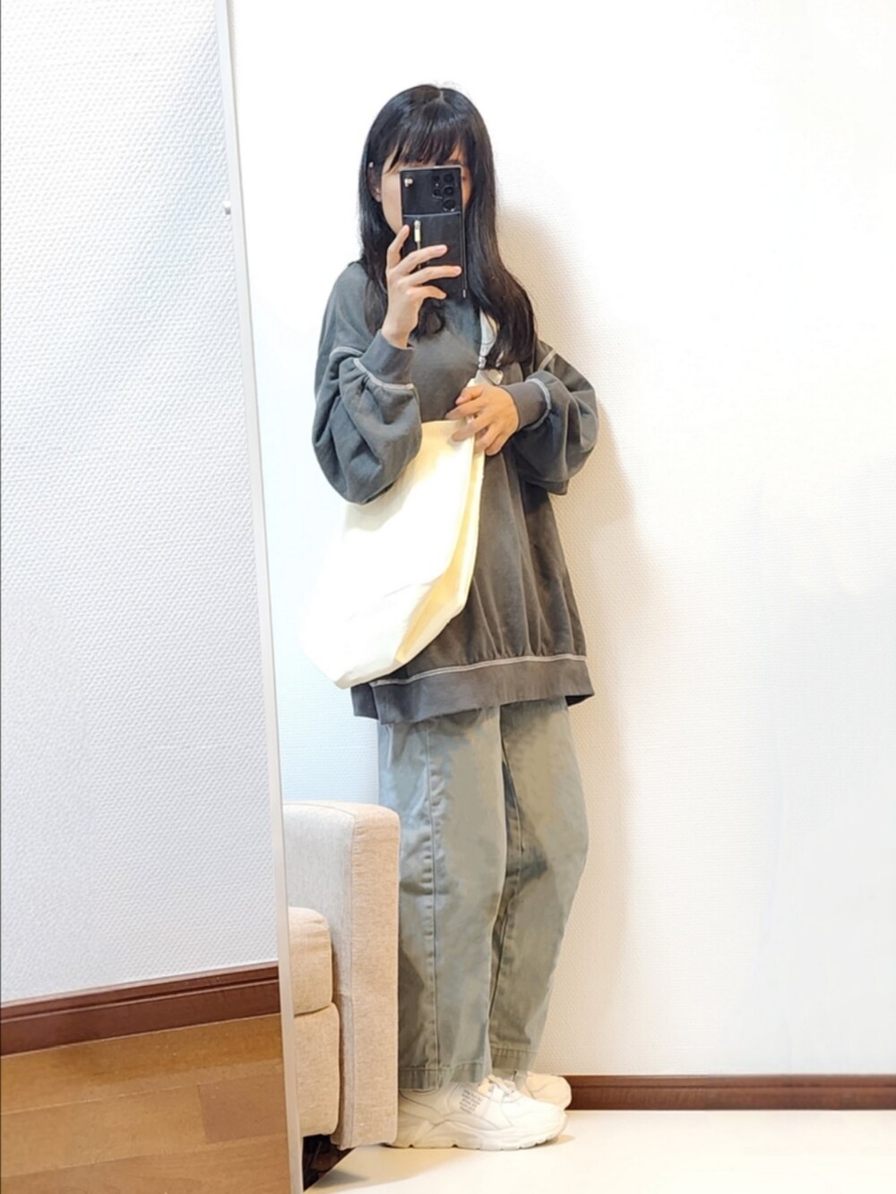 グレー系のTシャツ/カットソー、グリーン系のデニムパンツ、ホワイト系のスニーカーを着用したレディースの秋コーディネートの2枚目の写真