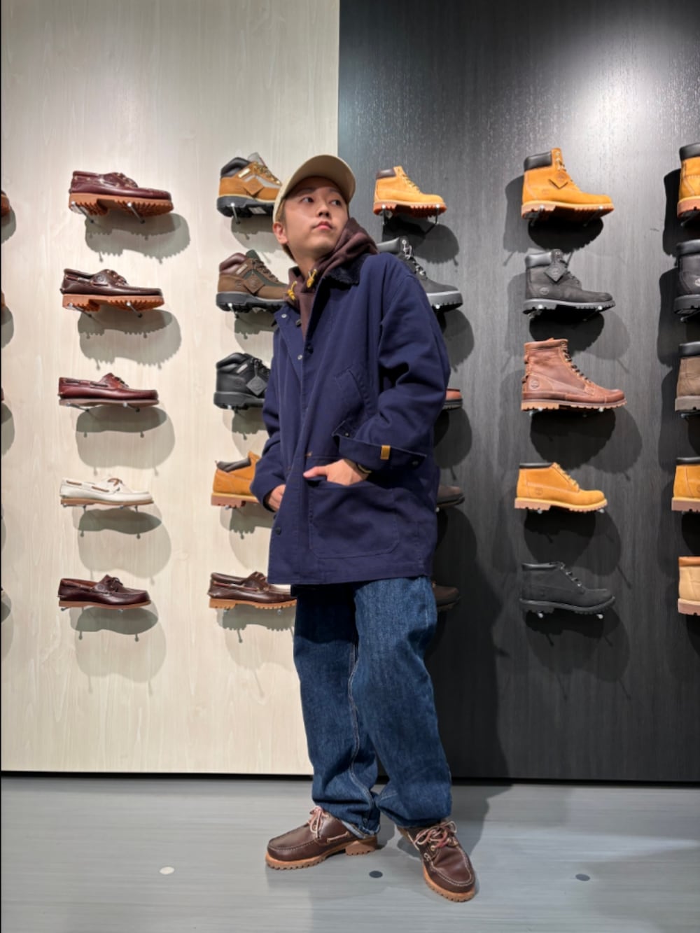 ブラウン系のパーカー、ブルー系のピーコート、ブルー系のデニムパンツを着用したメンズの秋コーディネートの3枚目の写真