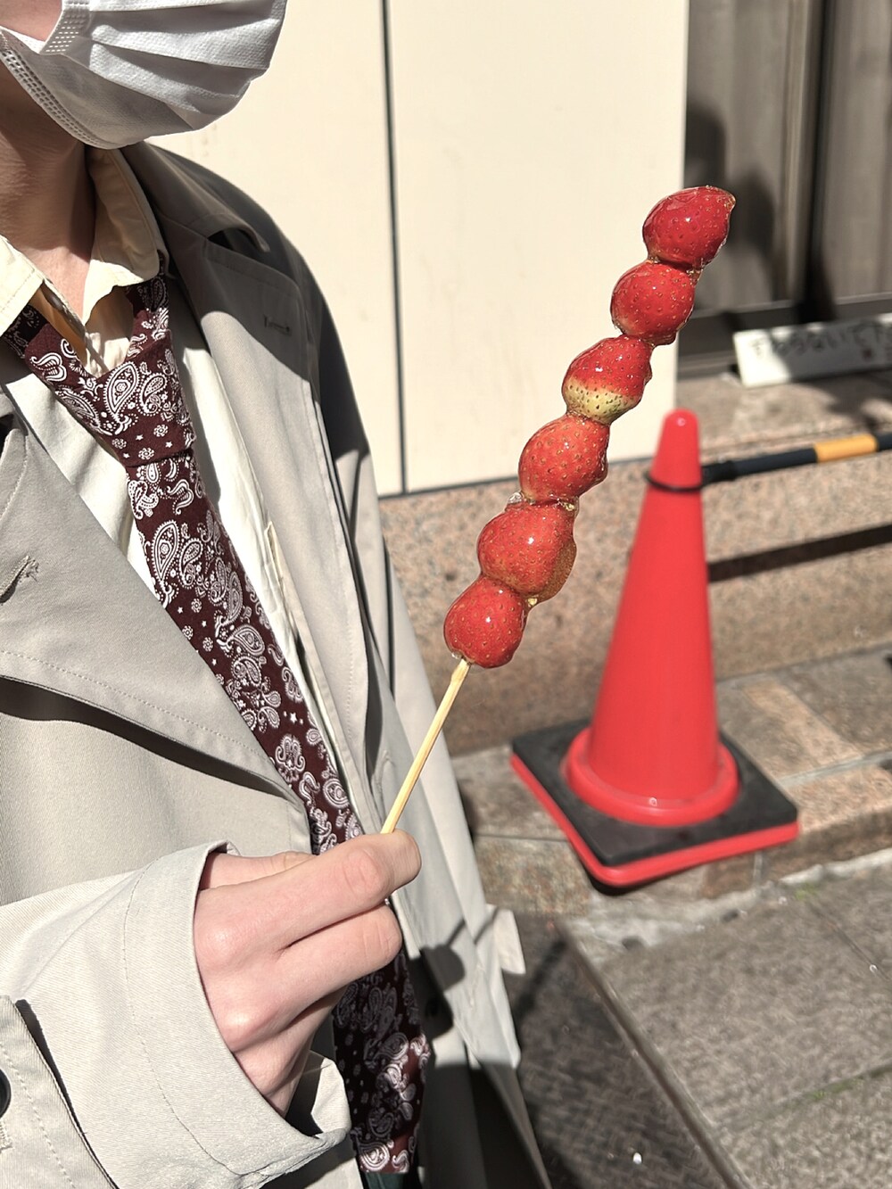 ベージュ系のチェスターコート、グリーン系のスラックス、ブラック系のその他シューズを着用したメンズの春コーディネートの2枚目の写真