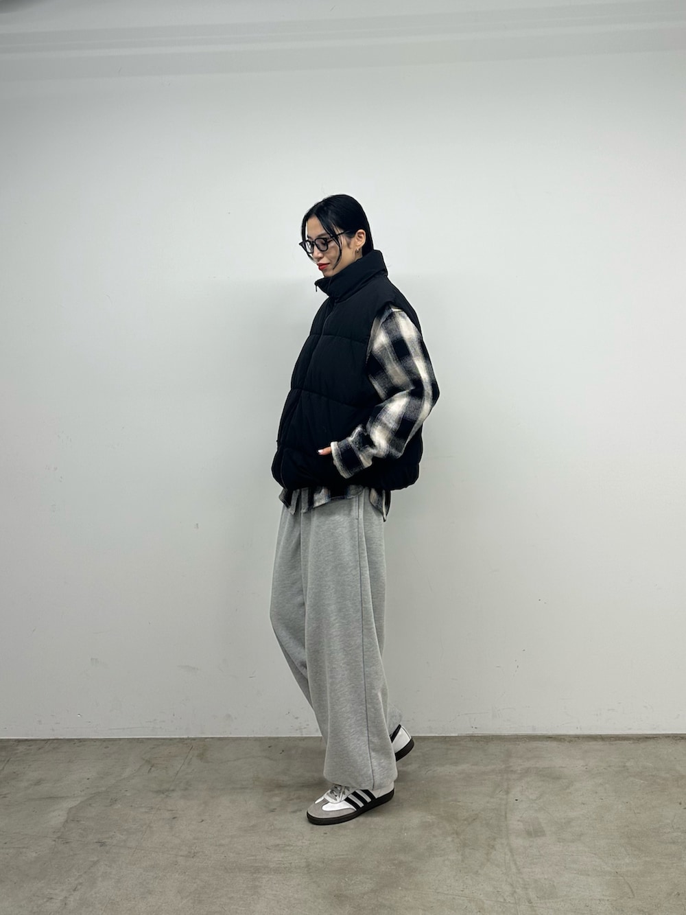 グレー系のスウェットパンツ、ブラック系のダウンベスト、ブラック系のトップスを着用したレディースの秋コーディネートの4枚目の写真