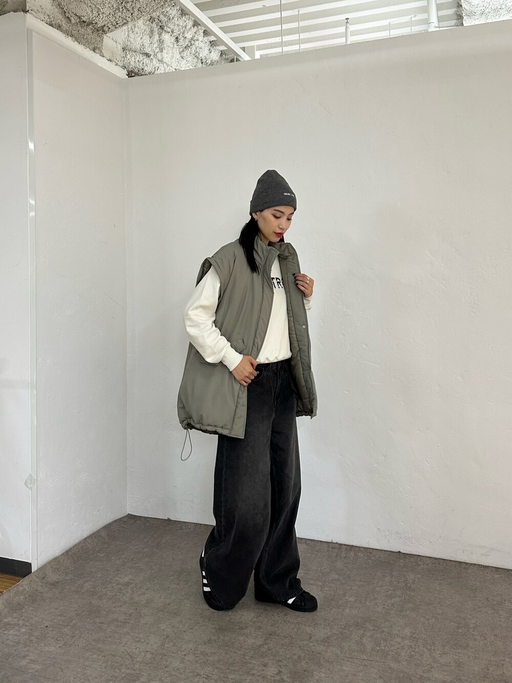 グリーン系のダウンジャケット/コート、ホワイト系のスウェット、ブラック系のデニムパンツを着用したレディースの秋コーディネートの2枚目の写真