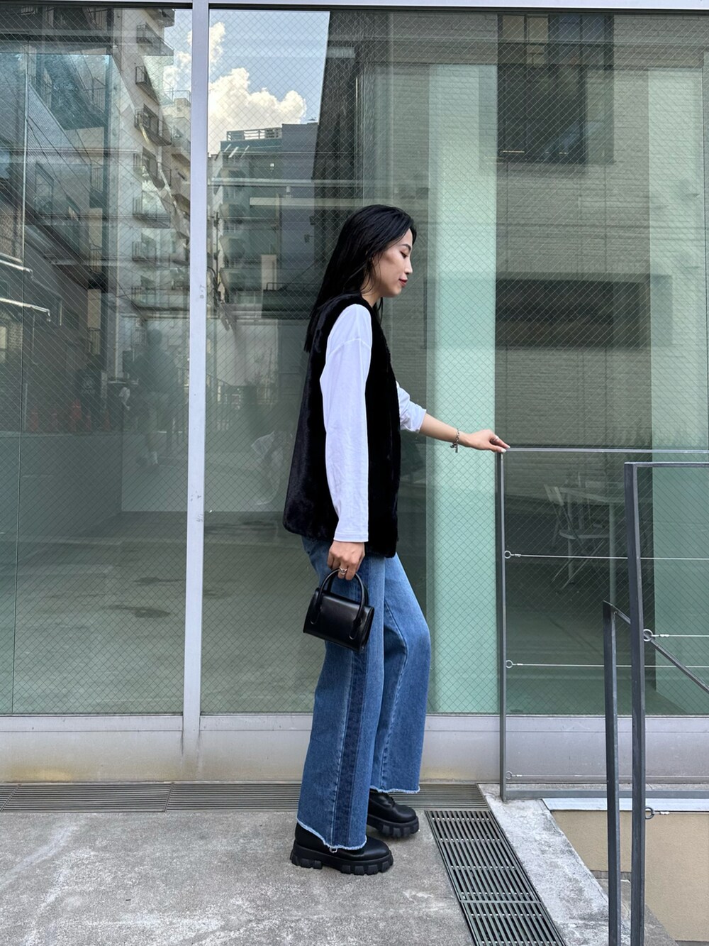 ブルー系のデニムパンツ、ホワイト系のTシャツ/カットソー、ブラック系のジャケット/アウターを着用したレディースの夏コーディネートの2枚目の写真