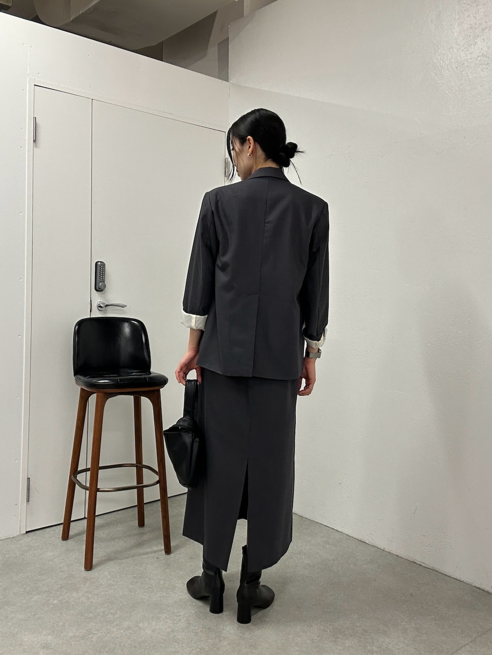 グレー系のテーラードジャケット、グレー系のドレス、ブラック系のハンドバッグを着用したレディースの冬コーディネートの3枚目の写真