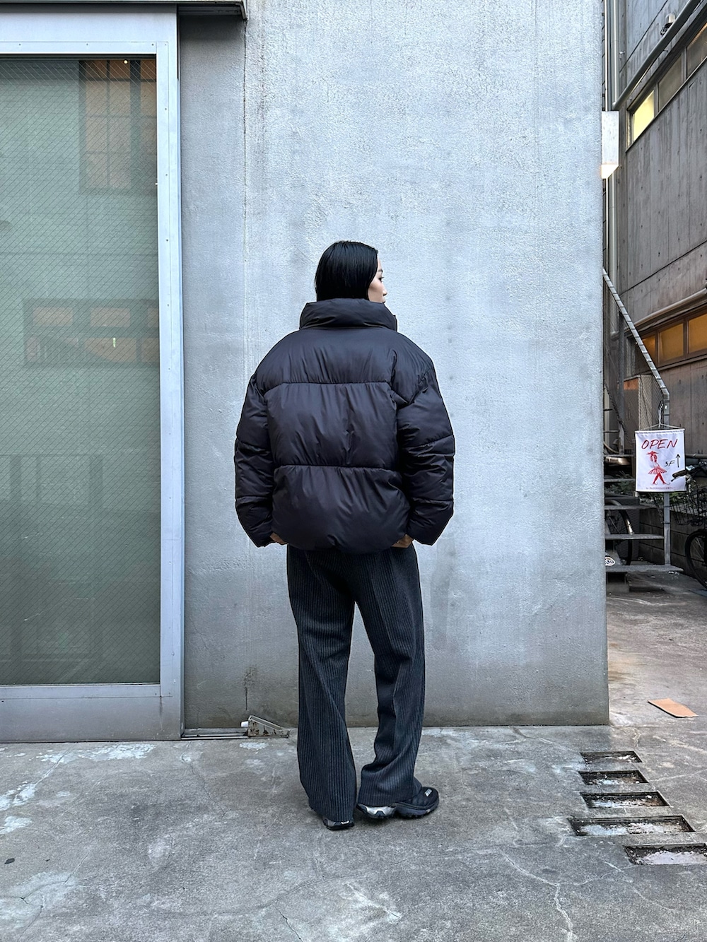 グレー系のスラックス、ブラック系のダウンジャケット/コート、グレー系のニット/セーターを着用したレディースの冬コーディネートの3枚目の写真